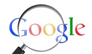 Logo de Google grossit à la loupe pour illustrer l'importance du SEO et SEA